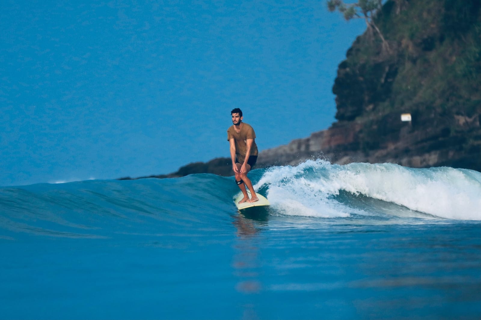 Simon longboarding in front of a headland